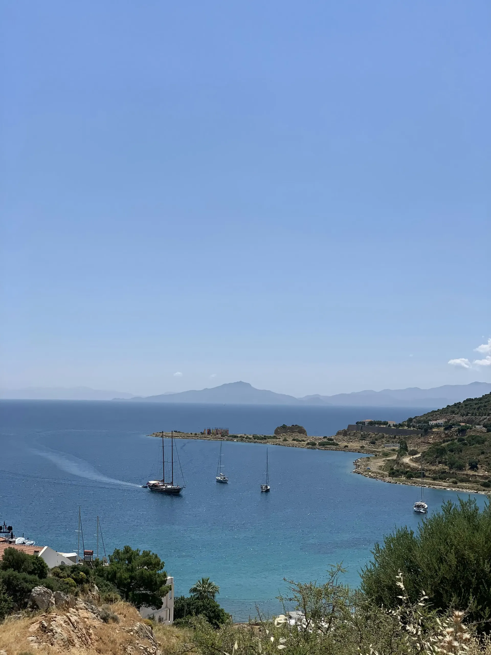 Datça'da bir koy — turkuaz denizde tekneler, arkada yarımadanın tepeleri
